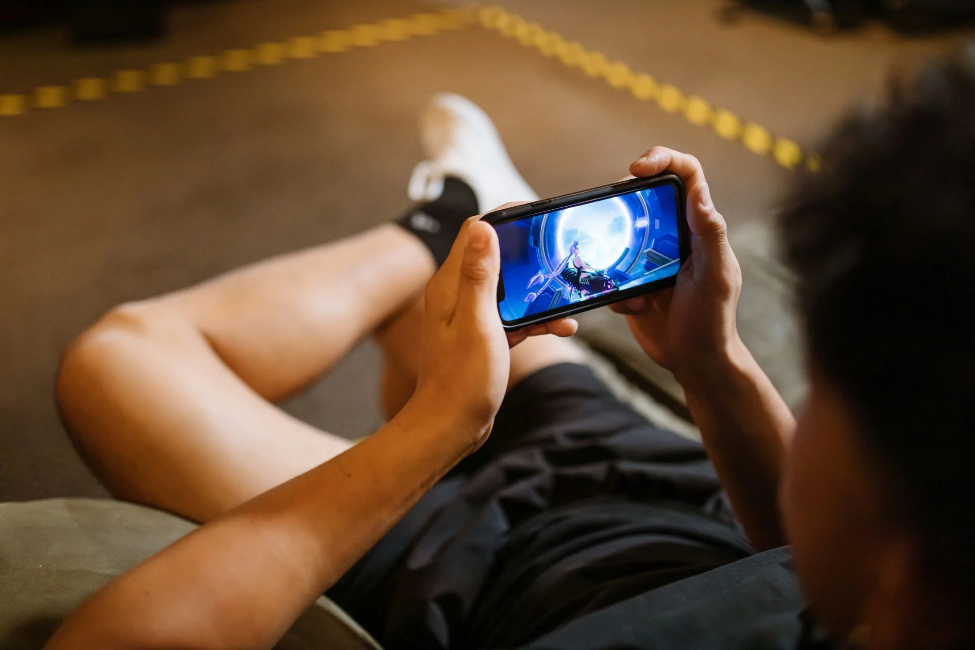Teen playing a mobile game on their phone — gaming communities are a common danger zone where predators target kids on Discord
